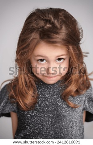 Portrait of a cute little girl smiling cheerfully at the camera on a light grey background. Kids concept.
