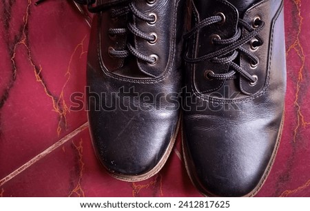 A pair of men's formal shoes made from black leather with attached shoelaces seen from the top