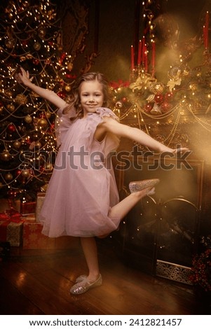 Children's Christmas and New Year. Full-length portrait of a beautiful little girl in a fluffy festive dress dancing in a fairytale Christmas setting. Evening fashion for children. 