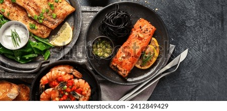 Grilled salmon fish fillet with lemon and strimps. Sea food dishes assorty. Healthy concept. Top view, copy space, banner Royalty-Free Stock Photo #2412849429