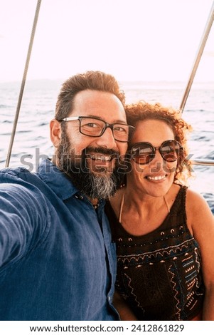 Cheerful people happy adult caucasian couple take selfie picture and enjoy together summer holiday vacation sailing with boat with ocean and sky in background - tourists lifestyle and fun in outdoor