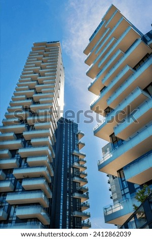 From below exterior of multistory residential skyscrapers located in Milan Italy Europe in sunny daylight against blue sky with clouds