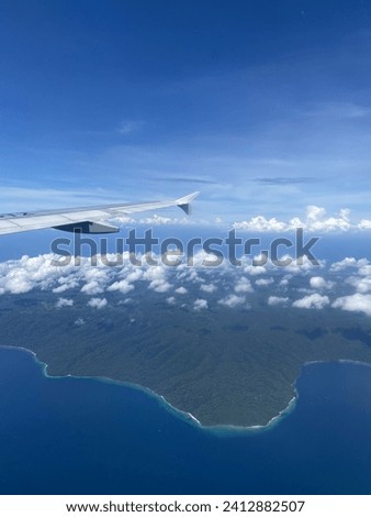 A picture that shows the island of Bali, Indonesia from up above the sky on an airplane window