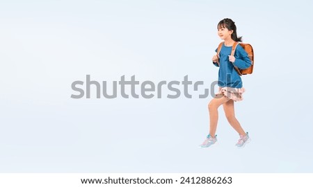 Elementary school girl jumping with a school bag on her back.