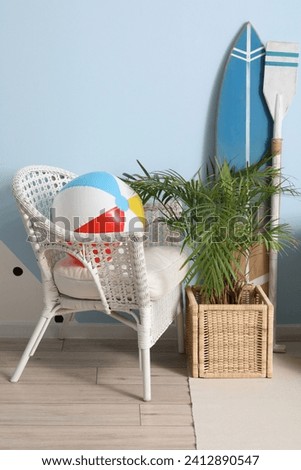 Interior of living room with armchair, surfing board and beach ball