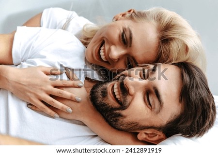 A young couple in casual clothing, happily embracing and laughing together, embodying love, joy, and emotional connection, with a background that enhances the mood of happiness and togetherness.