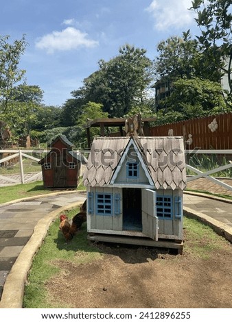A small house-shaped chicken coop, in a small zoo.