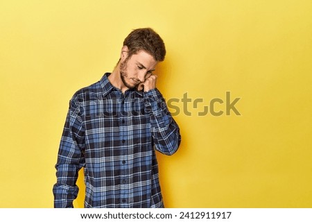 Young Caucasian man on a yellow studio background who feels sad and pensive, looking at copy space.