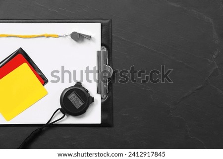 Referee equipment. Whistle, clipboard, cards and stopwatch on black table, top view with space for text