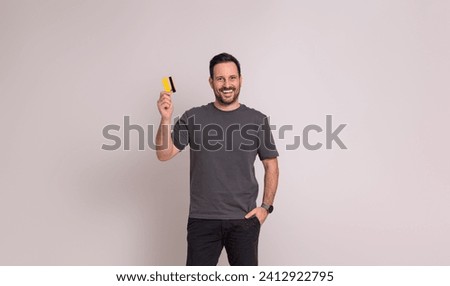 Portrait of happy young businessman with hand in pocket showing credit card on white background