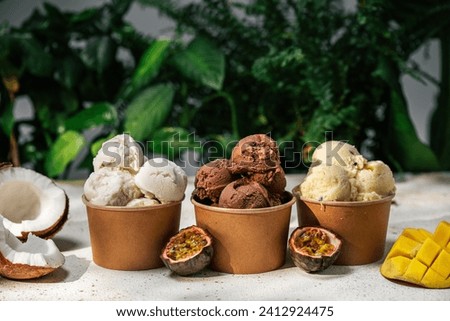 Homemade vegan coconut, mango and chocolate ice cream in paper cups against green natural background