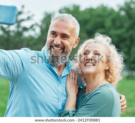 Happy active mid aged couple taking selfie in park or in nature outdoors. Love togetherness and acive seniors vitality concept