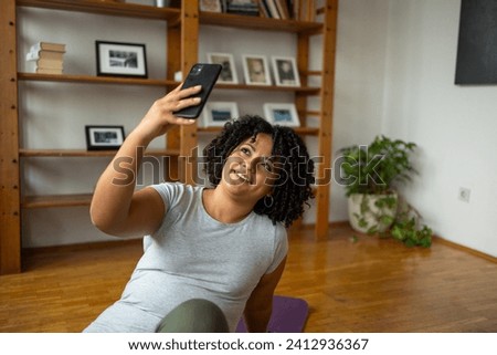 Happy woman taking selfie through smartphone in yoga room at home