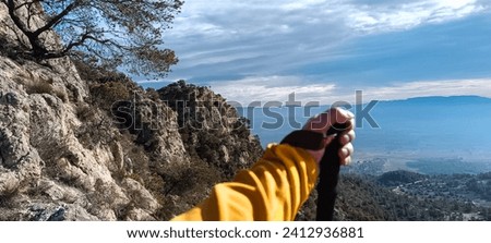 Anonymous male traveler with trekking pole standing on hill in highlands