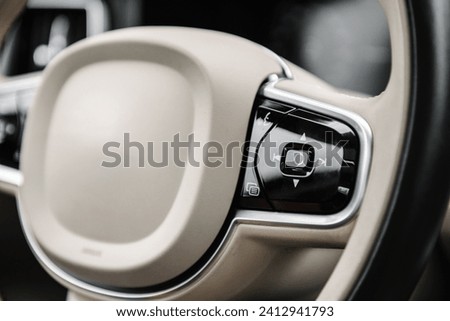 Helm of car, steering wheel close up. Modern interior in an expensive complete set. Control buttons of adaptive cruise, onboard computer management, lane keeping system. Car interior from the inside. Royalty-Free Stock Photo #2412941793