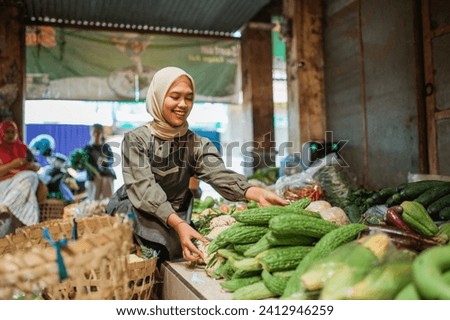 female seller arranging greens in vegetable stall at farmer market