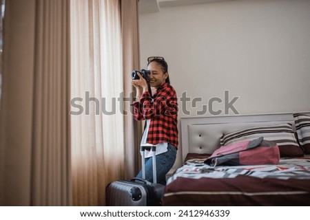 woman traveler taking pictures outside the window with a camera from inside the hotel room