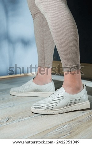 Female legs in white casual sneakers. Comfortable women's summer shoes.