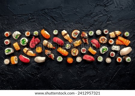 Sushi. An assortment of rolls, maki, nigiri etc, overhead flat lay composition on a black background, with copy space. Japanese restaurant menu design