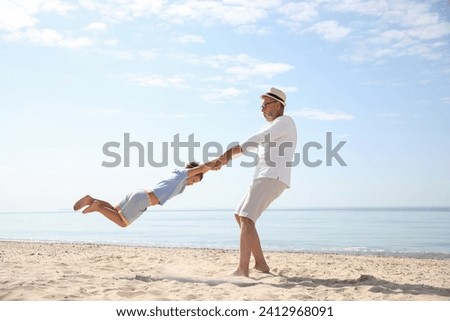 Grandfather playing with little boy on sea beach Royalty-Free Stock Photo #2412968091