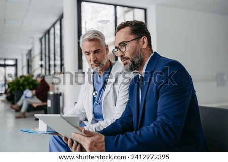 Pharmaceutical sales representative talking with doctor in medical building. Ambitious male sales representative presenting new medication. Royalty-Free Stock Photo #2412972395