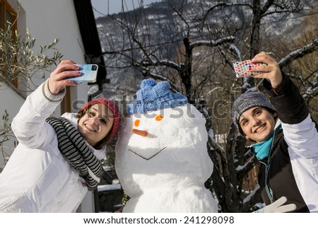 selfie with young girls and a snow man in winter background