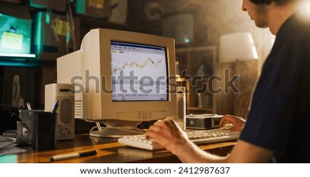 Back View Of Caucasian Male Software Engineer Programming on Old Desktop Computer In Retro Garage. Focused Man Starting Tech Startup Company In Nineties. Coding Innovative Online Service At Home. Royalty-Free Stock Photo #2412987637