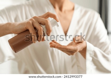 Woman applying self-tanning product onto hand, closeup Royalty-Free Stock Photo #2412993377
