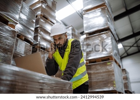 Warehouseman checking delivery, stock in warehouse on computer, pc. Warehouse manager using warehouse management software, app. Royalty-Free Stock Photo #2412994539