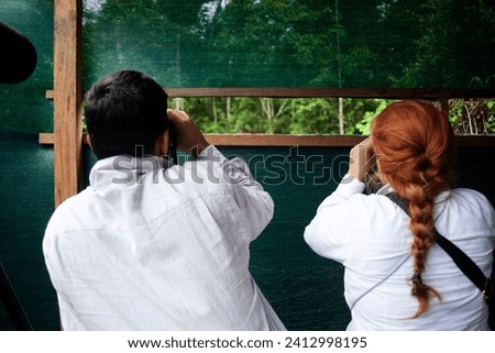 Couple watching birds in Amazon river and forest, Peru