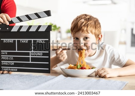 Young talented actor boy in front of the camera eating spaghetti for lunch.
