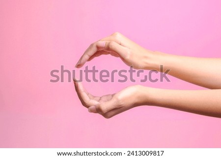 Woman making cupped rounded frame with two hands isolated on pink pastel background