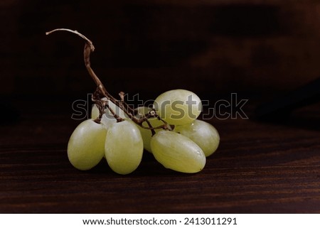 Small bunch of ripe green grapes on a wooden background.