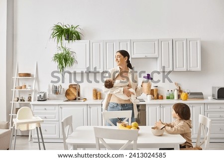 merry attractive mother enjoying breakfast with her toddler and newborn sons, modern parenting