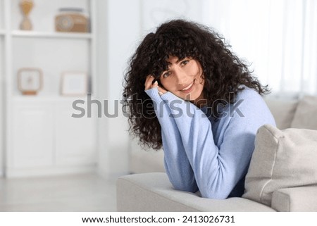 Happy young woman in stylish light blue sweater indoors, space for text