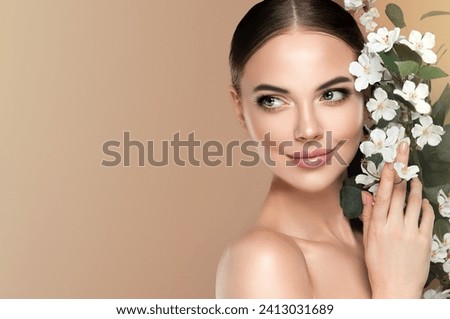 Beautiful young woman with clean fresh skin touching her face in flowers  . Girl facial  treatment   . Cosmetology , beauty  and spa . Female  model, care concept  Royalty-Free Stock Photo #2413031689