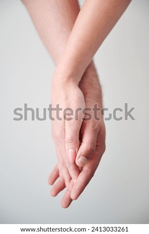 Close up view of hands of sweet couple. Young man and woman holding hands on light neutral background. Concept of love, intimacy, support, and trust. Royalty-Free Stock Photo #2413033261