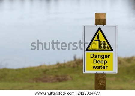 Danger Deep Water sign on a wooden post next to a lake