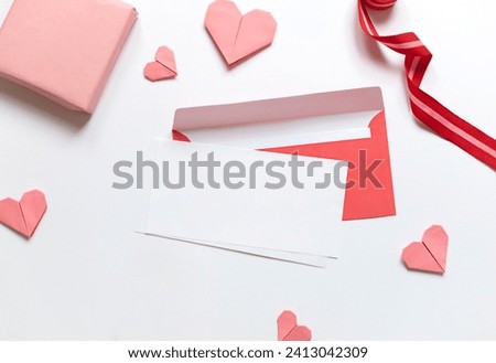 Red paper envelope with white blanks and pink origami hearts. Valentine's day concept card. Copy space