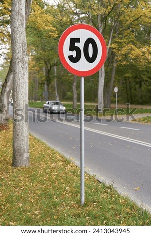 50 kilometers per hour limit road sign at the entrance to the town in the middle of the greenery. Warning to slow driving on street. Traffic sign. Speed limit for 50 km.