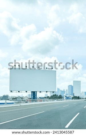 Empty Billboard along a highway with buildings on the background and blue sky with beautiful clouds. copy space.