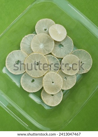 Directly above shot of lemon slices in container on green background. 