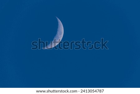 Growing crescent moon on the blue sky.