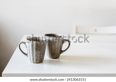 Two porcelain grey cups are on the white table.