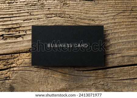 Black business card on wooden table, top view