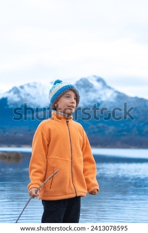 Boy in winter outdoors with woolen hat with snowy mountains behind