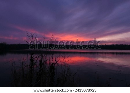 Beautiful pink and blue sky at sunrise or sunset. View of a lake in an idyllic landscape.