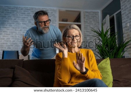 Man Arguing while Women Feeling Stressed on Sofa. Senior couple fighting at home. Female ignoring boyfriend while fighting on the sofa in modern apartment. Mature man quarreling with his wife at home Royalty-Free Stock Photo #2413100645