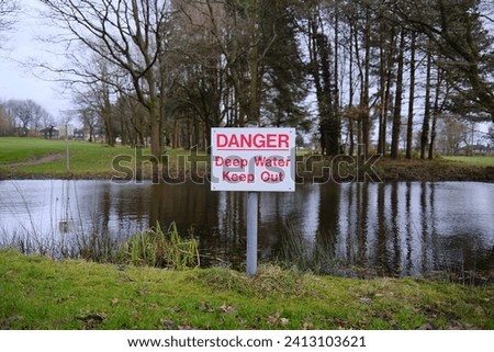 danger deep water warning sign by a water filled pond risk to the public of drowning