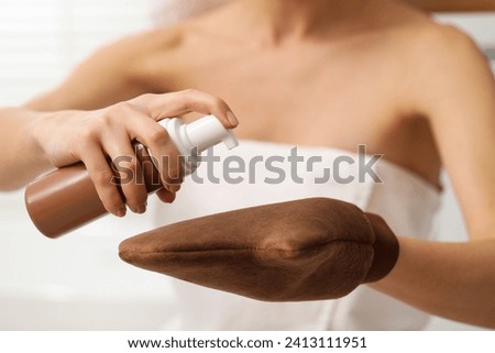 Self-tanning. Woman applying cosmetic product onto tanning mitt indoors, closeup Royalty-Free Stock Photo #2413111951